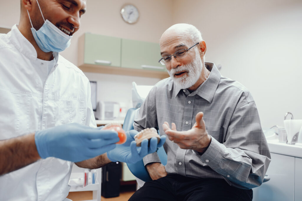 Dentist explaining to elderly man How Aging Affects Oral Health