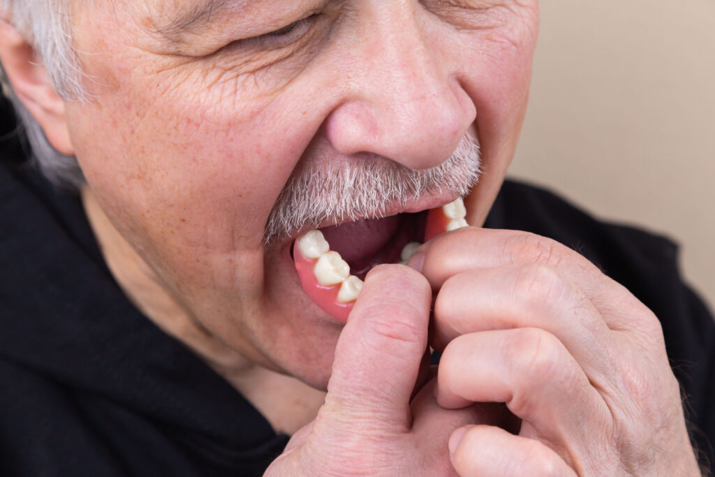 Elderly man putting dentures in mouth