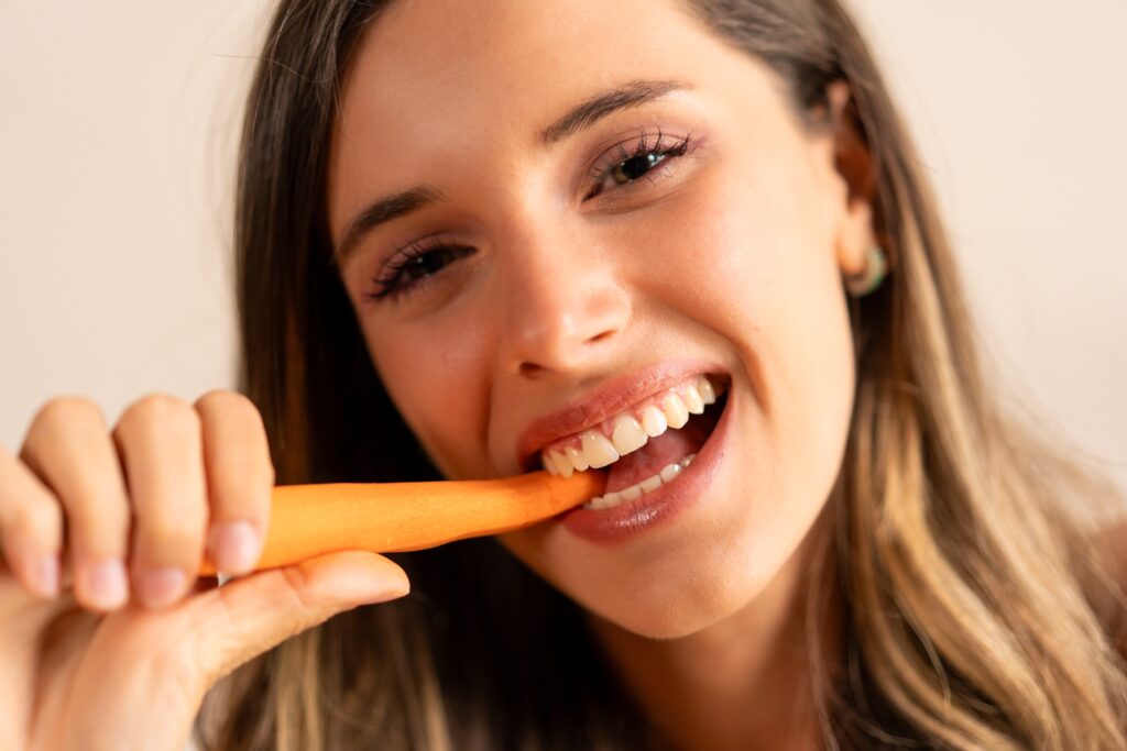 woman with strong and healthy teeth eating a carrot